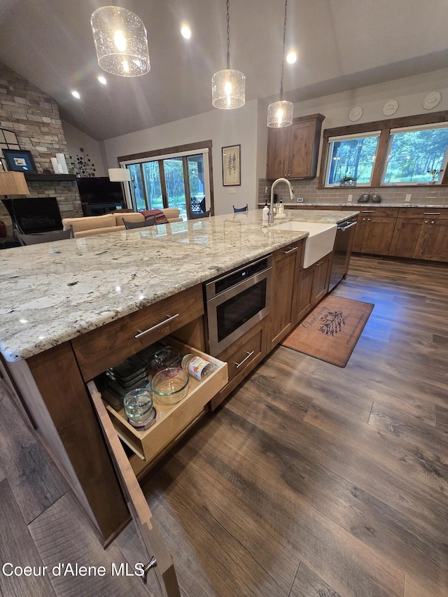 12552 N Walden Loop, Rathdrum, ID 83858 - kitchen featuring lofted ceiling, stainless steel microwave, dark wood-style flooring, plenty of natural light, and light stone countertops