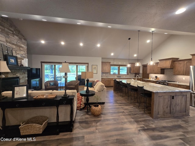 12552 N Walden Loop, Rathdrum, ID 83858 - living room featuring high vaulted ceiling, dark wood finished floors, a stone fireplace, healthy amount of natural light, and recessed lighting