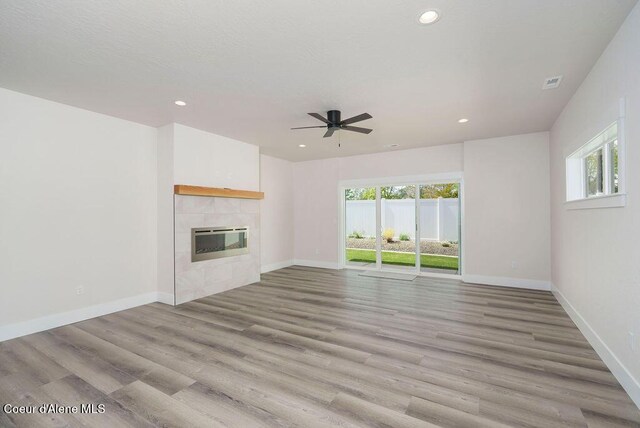 7291 N Grafton St, Coeur Dalene, ID 83815 - unfurnished living room with a ceiling fan, recessed lighting, light wood-style flooring, a tiled fireplace, and baseboards