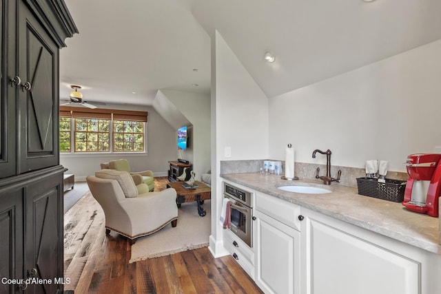 7783 S Buckrail Rd, Harrison, ID 83833 - kitchen featuring oven, a sink, open floor plan, dark wood finished floors, and white cabinetry