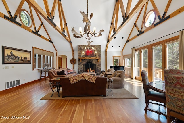 2672 Merril Martin Rd, Sagle, ID 83860 - living room featuring high vaulted ceiling, wood finished floors, arched walkways, a chandelier, and a lit fireplace