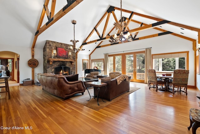 2672 Merril Martin Rd, Sagle, ID 83860 - living area featuring a chandelier, high vaulted ceiling, arched walkways, a stone fireplace, and hardwood / wood-style floors