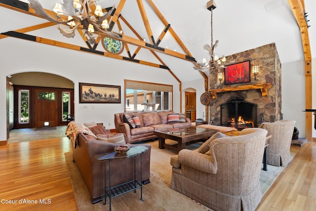 2672 Merril Martin Rd, Sagle, ID 83860 - living area featuring a chandelier, arched walkways, high vaulted ceiling, light wood-type flooring, and a stone fireplace