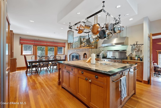 2672 Merril Martin Rd, Sagle, ID 83860 - kitchen featuring wall chimney exhaust hood, light wood-style flooring, brown cabinets, a center island, and recessed lighting