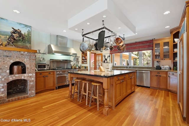 2672 Merril Martin Rd, Sagle, ID 83860 - kitchen with stainless steel appliances, wall chimney exhaust hood, light wood-style floors, recessed lighting, and a breakfast bar