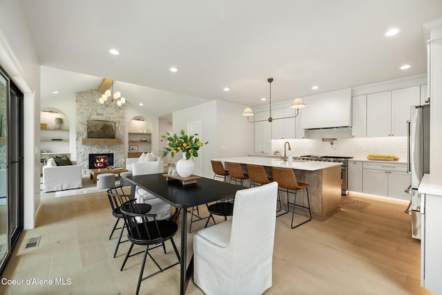11947 N Rocking R Rd, Hayden, ID 83835 - dining space with light wood-type flooring, a fireplace, a chandelier, lofted ceiling, and recessed lighting
