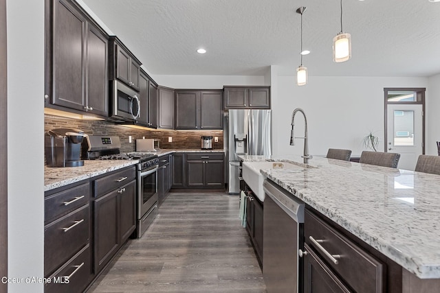 4463 E Marble Fox Ave, Post Falls, ID 83854 - kitchen with appliances with stainless steel finishes, a sink, dark brown cabinets, dark wood-type flooring, and decorative backsplash