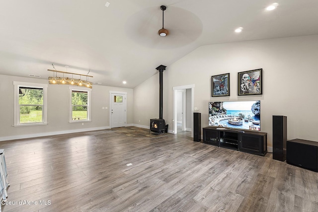 193 Grouse Rd, Sandpoint, ID 83864 - unfurnished living room featuring a wood stove, wood finished floors, vaulted ceiling, baseboards, and recessed lighting