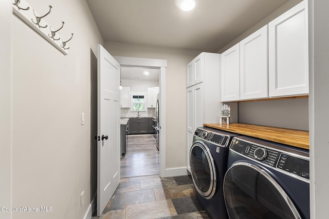 193 Grouse Rd, Sandpoint, ID 83864 - laundry area featuring cabinet space, washing machine and clothes dryer, stone tile flooring, and baseboards