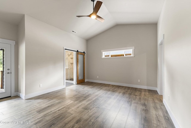 193 Grouse Rd, Sandpoint, ID 83864 - unfurnished bedroom featuring a barn door, wood finished floors, vaulted ceiling, baseboards, and a ceiling fan