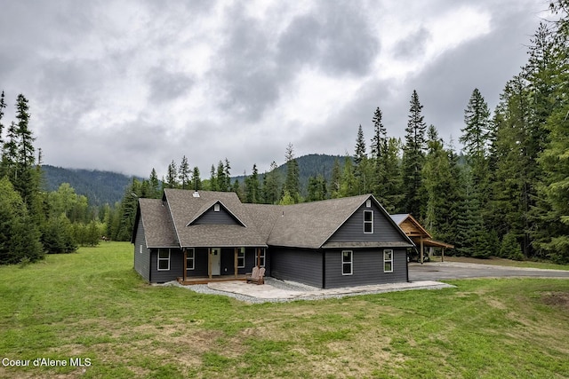 193 Grouse Rd, Sandpoint, ID 83864 - view of front of house featuring a forest view, a porch, a front lawn, and a mountain view