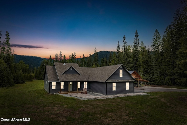 193 Grouse Rd, Sandpoint, ID 83864 - view of front facade with a front lawn, a forest view, a shingled roof, and covered porch