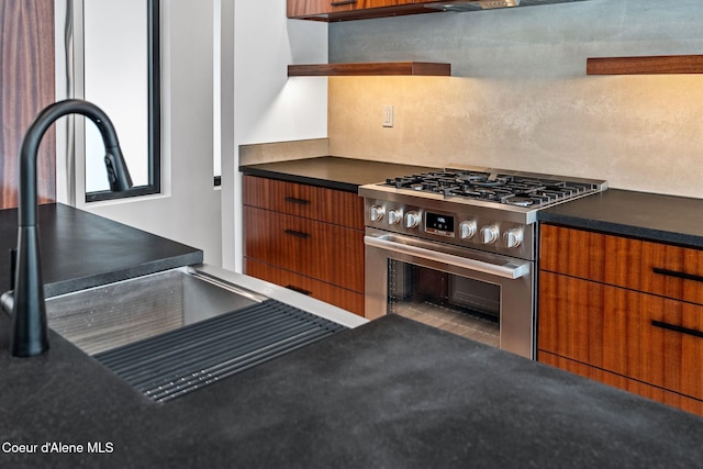 1808 Garfield Bay Rd, Sagle, ID 83860 - kitchen featuring stainless steel range with gas stovetop, dark countertops, brown cabinetry, modern cabinets, and a sink