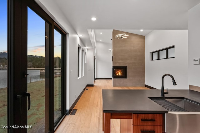 1808 Garfield Bay Rd, Sagle, ID 83860 - kitchen with a sink, light wood-type flooring, brown cabinets, a large fireplace, and dark countertops