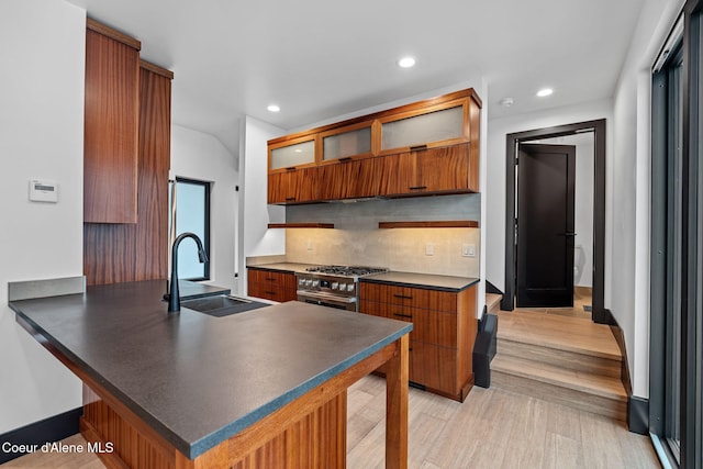 1808 Garfield Bay Rd, Sagle, ID 83860 - kitchen featuring a sink, dark countertops, a peninsula, high end stainless steel range oven, and glass insert cabinets