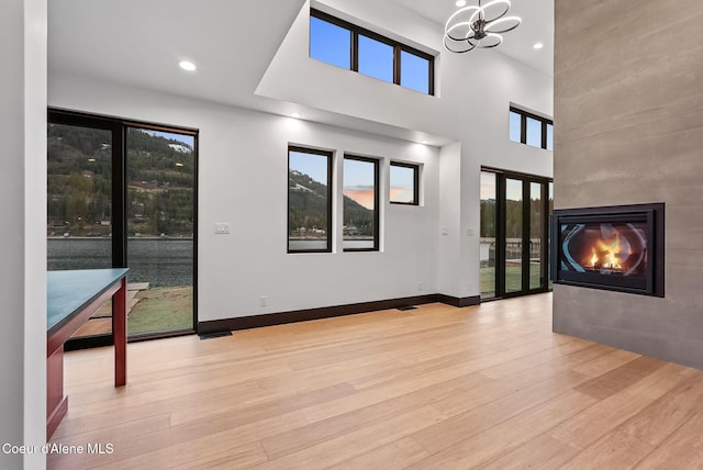 1808 Garfield Bay Rd, Sagle, ID 83860 - unfurnished living room with wood finished floors, a chandelier, a fireplace, a towering ceiling, and recessed lighting