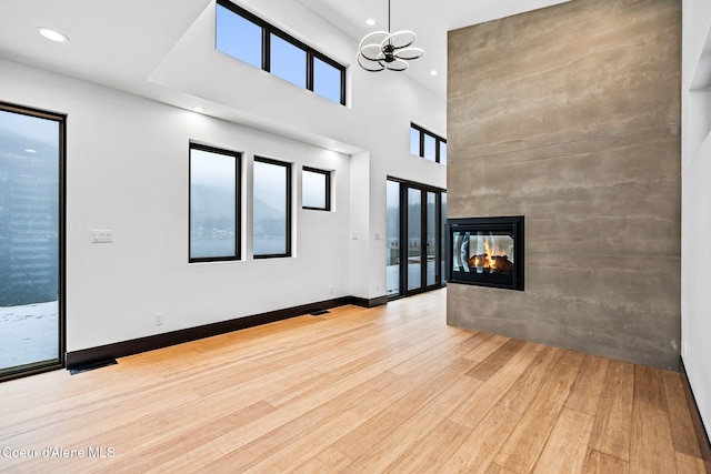 1808 Garfield Bay Rd, Sagle, ID 83860 - unfurnished living room featuring wood finished floors, a multi sided fireplace, a high ceiling, a chandelier, and recessed lighting