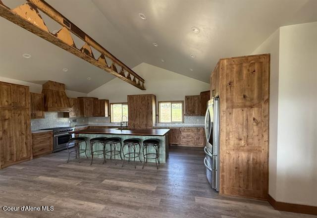 240 Canyon Dr, Kooskia, ID 83539 - kitchen featuring appliances with stainless steel finishes, custom exhaust hood, a kitchen bar, dark wood-type flooring, and a kitchen island