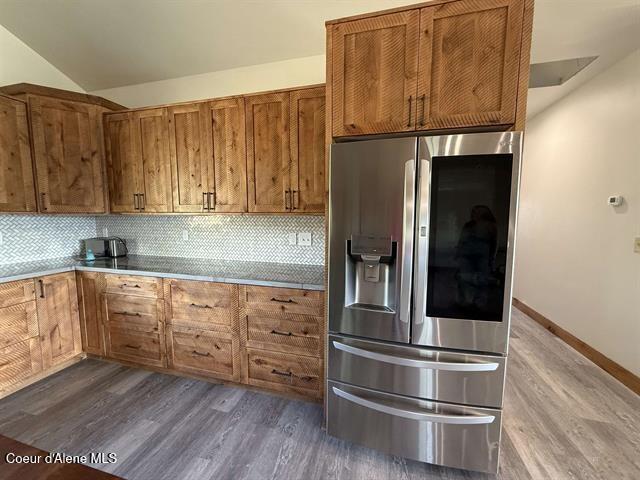 240 Canyon Dr, Kooskia, ID 83539 - kitchen featuring stainless steel refrigerator with ice dispenser, dark wood-type flooring, brown cabinets, backsplash, and lofted ceiling