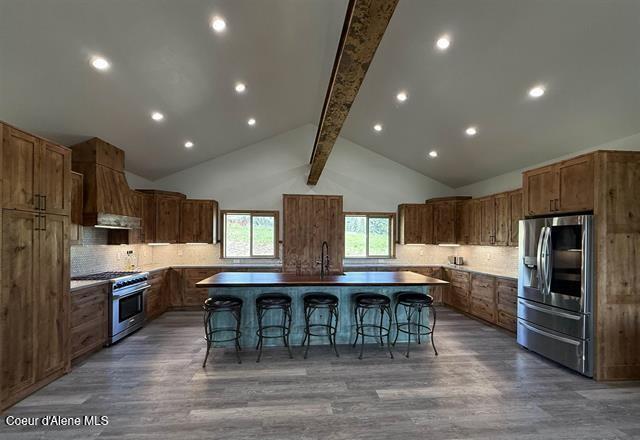 240 Canyon Dr, Kooskia, ID 83539 - kitchen with appliances with stainless steel finishes, a large island, beamed ceiling, wood finished floors, and a kitchen bar