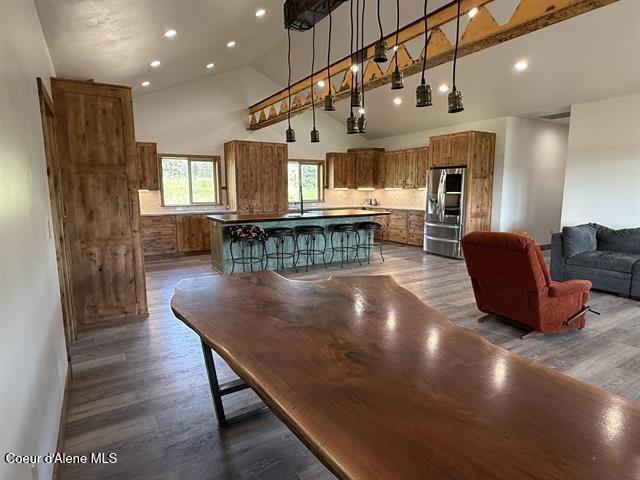 240 Canyon Dr, Kooskia, ID 83539 - kitchen with stainless steel fridge with ice dispenser, brown cabinets, high vaulted ceiling, dark wood finished floors, and a kitchen island