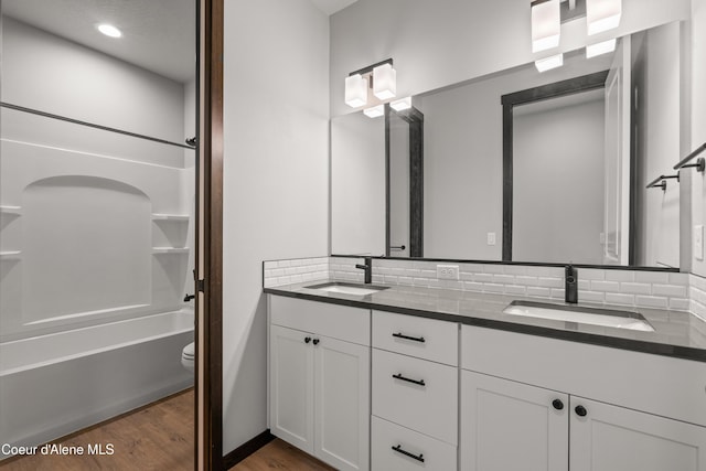 6568 N Downing Ln, Coeur Dalene, ID 83815 - full bathroom featuring double vanity, wood finished floors, tasteful backsplash, toilet, and  shower combination