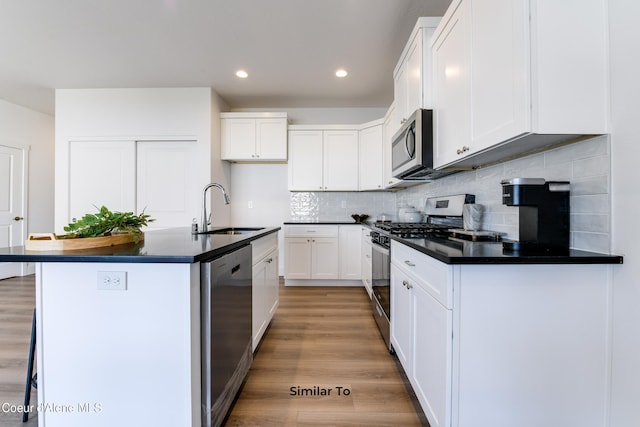 701 N Creative Way, Post Falls, ID 83854 - kitchen featuring a sink, appliances with stainless steel finishes, dark countertops, light wood finished floors, and tasteful backsplash
