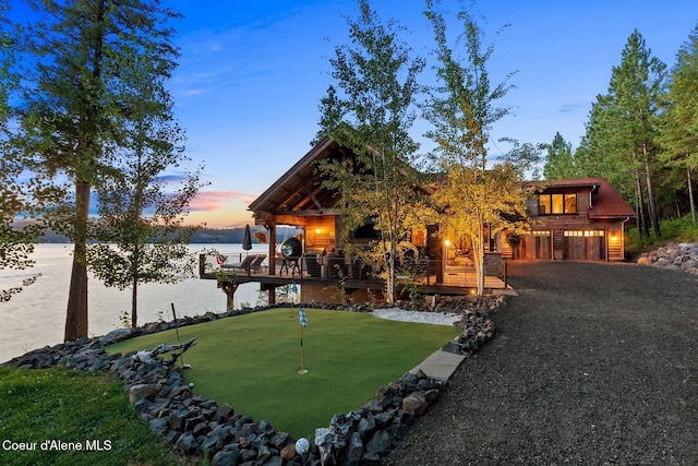 20890 S Inspiration Trl, Harrison, ID 83833 - view of front of home with a putting green, a water view, gravel driveway, and an attached garage