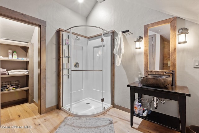 20890 S Inspiration Trl, Harrison, ID 83833 - bathroom featuring a sink, a shower stall, wood finished floors, baseboards, and vaulted ceiling