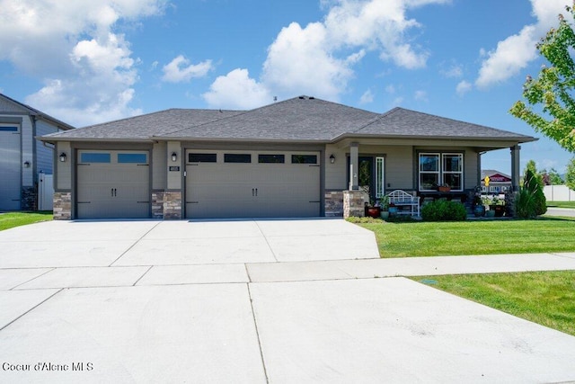 4615 N Connery Loop, Post Falls, ID 83854 - view of front of house featuring a front yard, driveway, a garage, covered porch, and stone siding