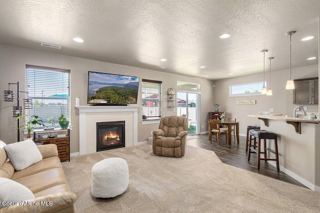 4615 N Connery Loop, Post Falls, ID 83854 - living area featuring carpet floors, a textured ceiling, baseboards, recessed lighting, and a glass covered fireplace