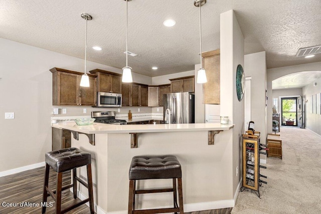4615 N Connery Loop, Post Falls, ID 83854 - kitchen with stainless steel appliances, a textured ceiling, arched walkways, baseboards, and a kitchen bar