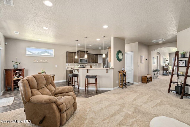 4615 N Connery Loop, Post Falls, ID 83854 - living area with arched walkways, a textured ceiling, baseboards, recessed lighting, and light colored carpet