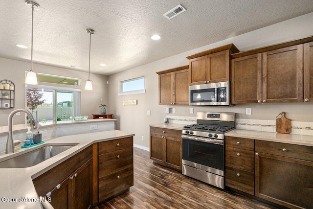 4615 N Connery Loop, Post Falls, ID 83854 - kitchen with stainless steel appliances, a sink, dark wood-type flooring, a textured ceiling, and decorative light fixtures