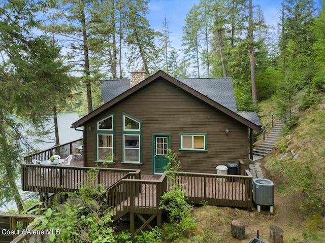 7373 E Hayden Haven Rd, Hayden, ID 83835 - rear view of property featuring a deck, a shingled roof, central AC unit, and a chimney