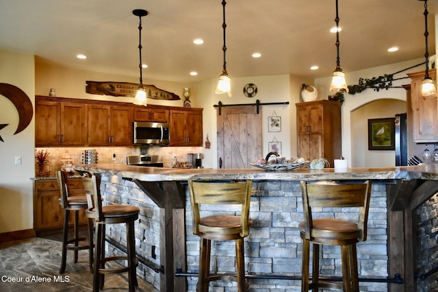 995 S Saddleback Dr, Coeur Dalene, ID 83814 - kitchen with appliances with stainless steel finishes, a breakfast bar, decorative backsplash, recessed lighting, and decorative light fixtures