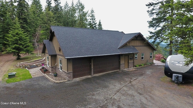995 S Saddleback Dr, Coeur Dalene, ID 83814 - rustic home with stone siding, a garage, a shingled roof, and dirt driveway