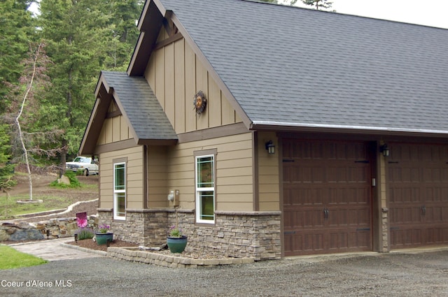 995 S Saddleback Dr, Coeur Dalene, ID 83814 - view of side of property with board and batten siding, stone siding, a garage, a shingled roof, and gravel driveway