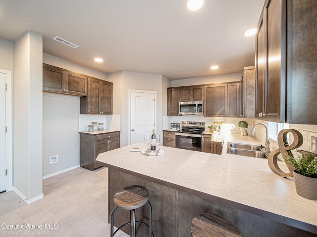 13639 N Apex Way, Hayden, ID 83835 - kitchen with stainless steel appliances, a sink, a peninsula, decorative backsplash, and baseboards
