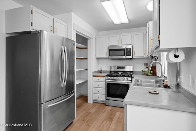 1125 N Shannon Ln, Post Falls, ID 83854 - kitchen featuring appliances with stainless steel finishes, a sink, light wood-style flooring, white cabinets, and light countertops
