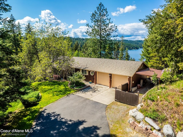 7485 E Revilo Point Rd, Hayden, ID 83835 - ranch-style home with a garage, driveway, a view of trees, roof with shingles, and a water view