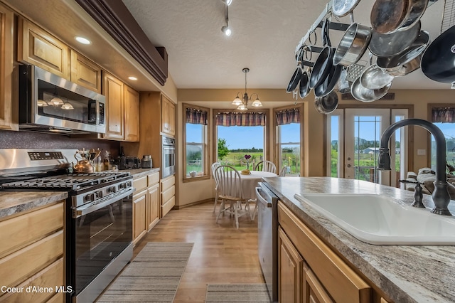 222 E Remington Rd, Athol, ID 83801 - kitchen featuring stainless steel appliances, a sink, light wood finished floors, a chandelier, and decorative light fixtures