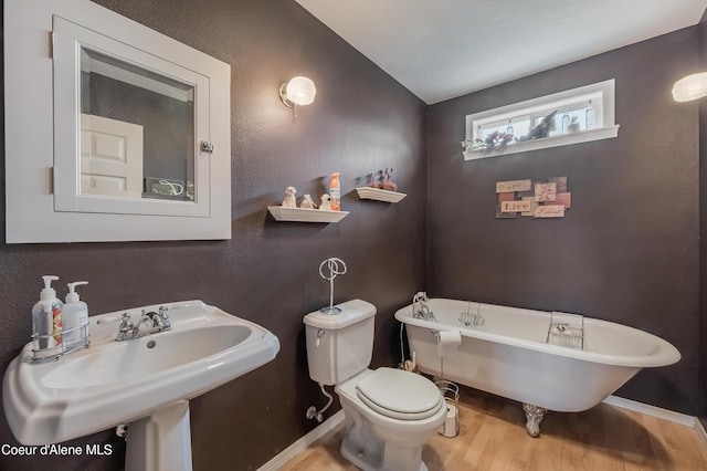 222 E Remington Rd, Athol, ID 83801 - bathroom featuring wood finished floors, toilet, a soaking tub, a sink, and baseboards