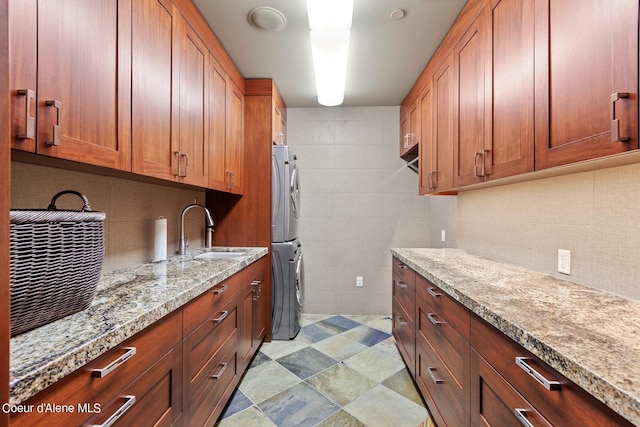2051 S Island Green Dr, Coeur Dalene, ID 83814 - kitchen with a sink, stacked washing machine and dryer, light stone counters, tile walls, and decorative backsplash