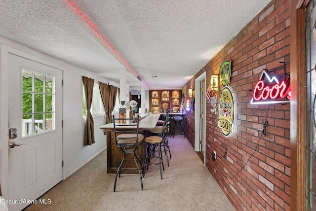 291 Comeback Bay Ln, Sagle, ID 83860 - dining room featuring brick wall, carpet flooring, a textured ceiling, and bar