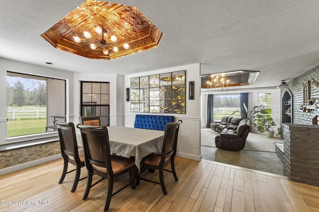 7104 W Kidd Island Rd, Coeur Dalene, ID 83814 - dining room featuring a chandelier, hardwood / wood-style floors, a textured ceiling, plenty of natural light, and baseboards