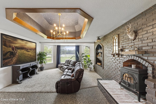 7104 W Kidd Island Rd, Coeur Dalene, ID 83814 - living area featuring a wood stove, a tray ceiling, carpet floors, a chandelier, and brick wall