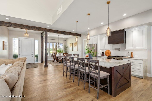 1831 E Dalton Ave, Dalton Gardens, ID 83815 - kitchen featuring custom exhaust hood, open floor plan, freestanding refrigerator, a kitchen breakfast bar, and white cabinets