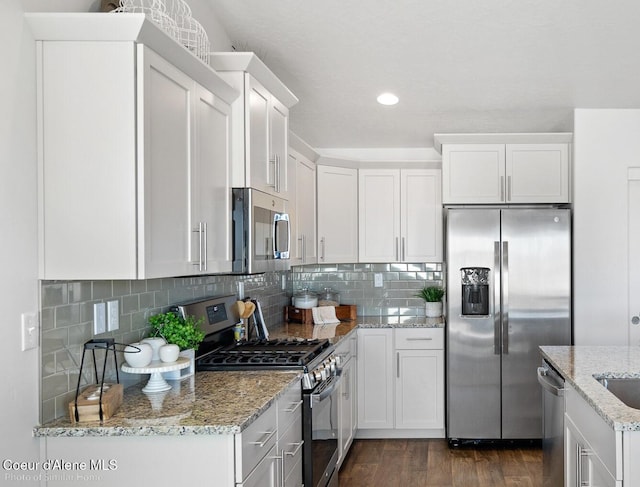 13659 N Apex Way, Hayden, ID 83835 - kitchen with appliances with stainless steel finishes, dark wood finished floors, decorative backsplash, white cabinets, and recessed lighting