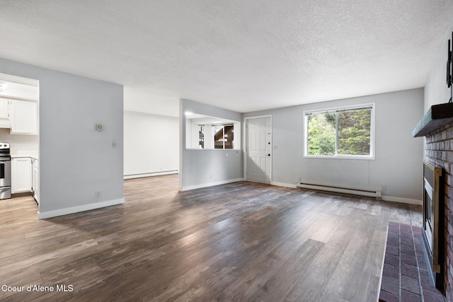 64 Winterbrook Way Unit 101, Sandpoint, ID 83864 - unfurnished living room with baseboard heating, a fireplace, wood finished floors, a textured ceiling, and a baseboard radiator
